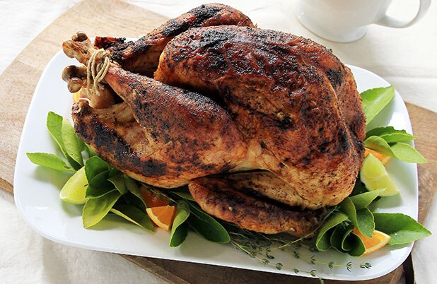 Un pavo entero frotado sobre un lecho de naranjas y salvia.